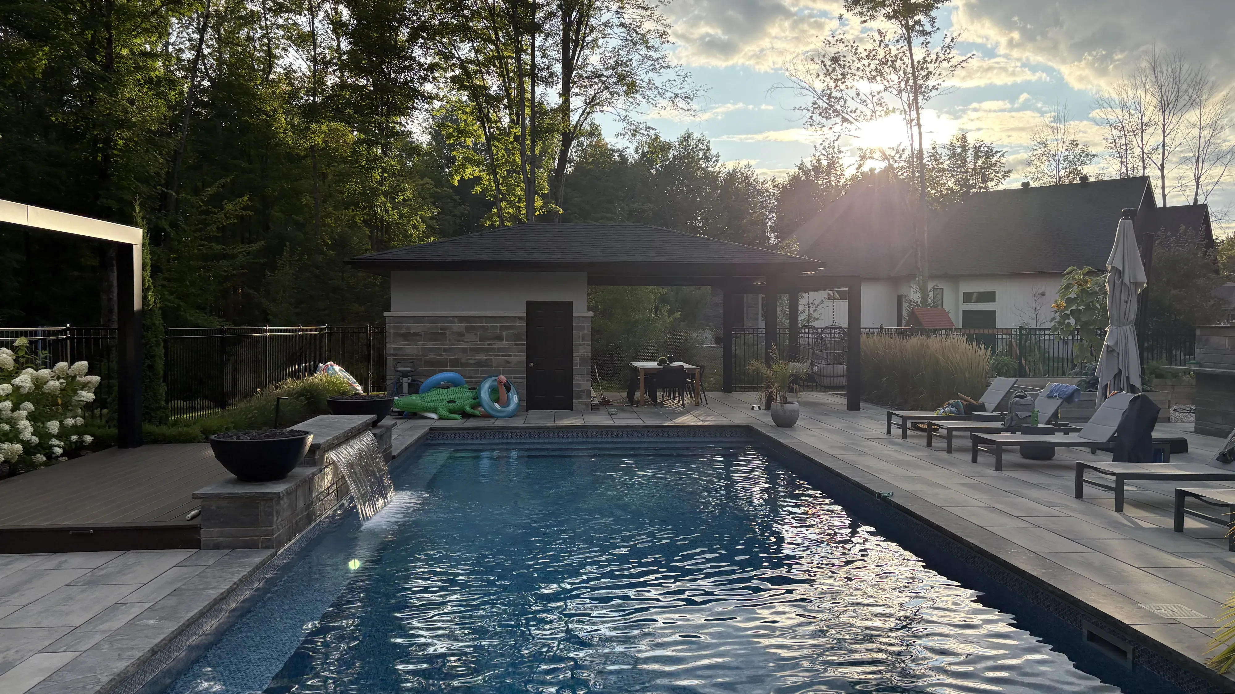 Inground pool, stone patio and covered pavilion in evening light