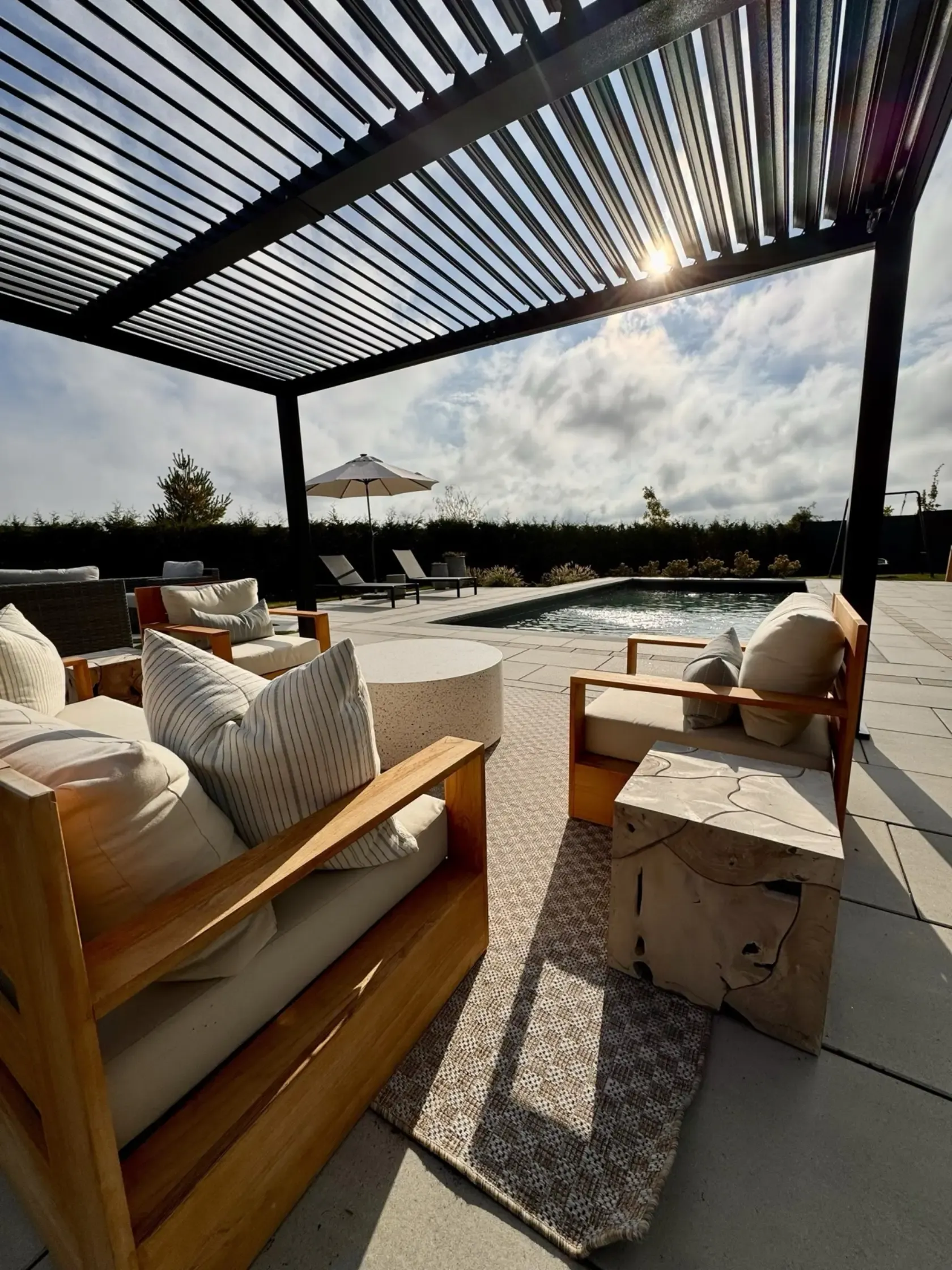 Louvered pergola over a teak lounge in golden sun flare